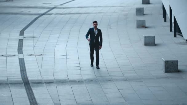 Мужчина ходит в стильном костюме на улице. Бизнесмен швыряет бумаги на улицу — стоковое видео