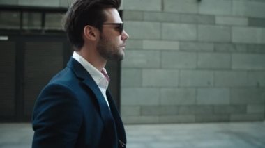 Side view businessman walking in suit. Man wearing sunglasses at street