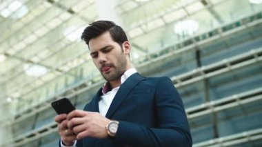 Portrait businessman using smartphone. Man standing with phone in hand outdoors