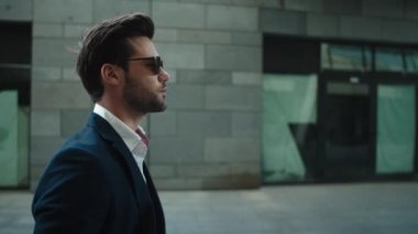 Portrait man wearing sunglasses at street. Man turning head in suit outside
