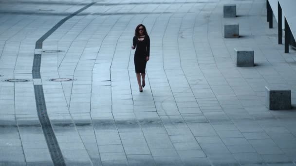Женщина идет в замедленной съемке на тротуаре. Женщина снимает очки на улице — стоковое видео