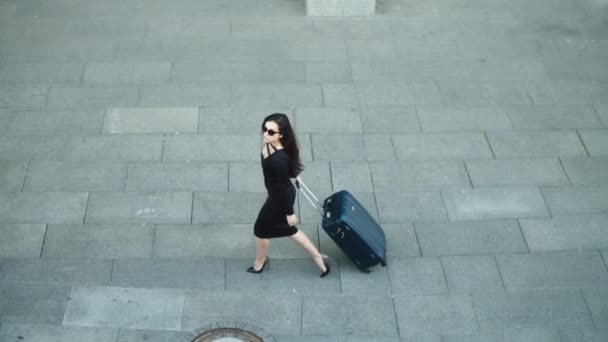 Donna vista laterale che cammina con la valigia. Donna guardando lontano in abito a strada — Video Stock