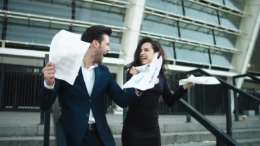 Couple throwing papers in slow motion. Couple celebrating victory together