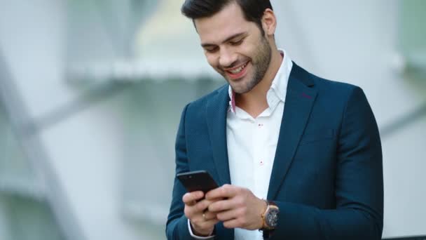 Porträtt affärsman med hjälp av smartphone. Man ler med telefonen i handen utomhus — Stockvideo