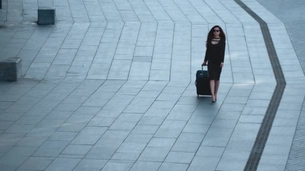 Mujer caminando con maleta en la calle. Mujer quitándose las gafas de sol afuera — Vídeo de stock