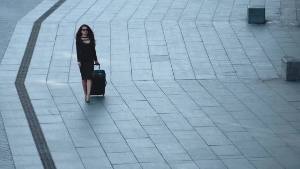 Een vrouw met bagage op straat. Vrouw kijkt weg met koffer op straat — Stockvideo