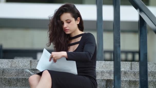 Una mujer de cerca leyendo documentos en la calle. Mujer sentada con papeles afuera — Vídeo de stock