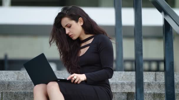 Een close-up vrouw zit op de trap met een laptop. Zakenvrouw werkt met notebook — Stockvideo