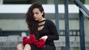 Closeup woman sitting with roses. Woman touching bouquet of roses on stairs