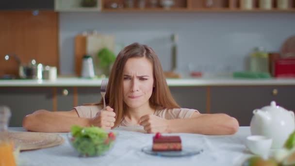 Woman choosing salad instead cake on kitchen. Girl with fork trying fresh salad — 비디오