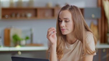 Businesswoman using laptop on kitchen. Lady eating corn flakes in slow motion