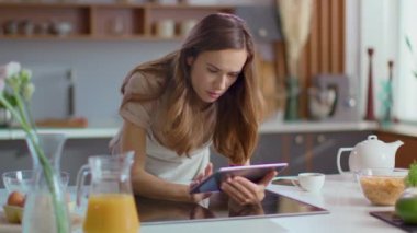 Woman using tablet computer in kitchen. Lady showing idea gesture at home