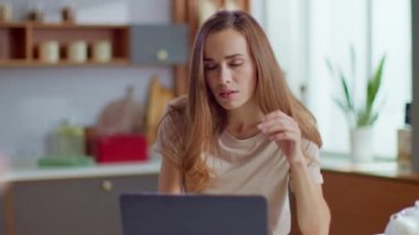 Businesswoman working on laptop computer at home. Woman using laptop on kitchen