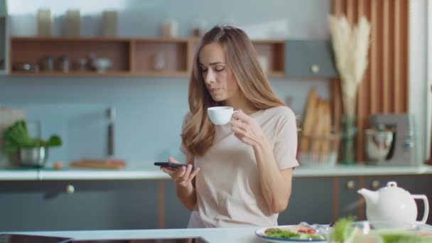 Woman taking selfie on smartphone at kitchen. Lady drinking coffee in morning — Αρχείο Βίντεο