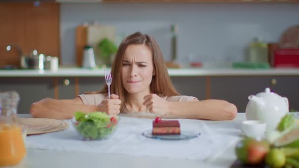 Woman choosing cake instead salad on kitchen. Lady eating cake on kitchen — ストック動画