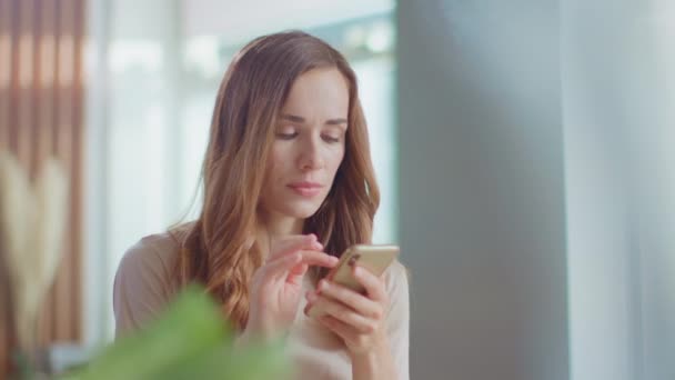 Γυναίκα διαβάζει καλά νέα στο smartphone στο σπίτι. Κορίτσι που χρησιμοποιεί κινητό εσωτερικό — Αρχείο Βίντεο