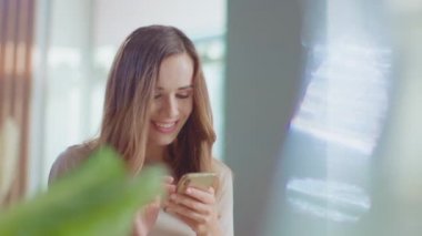 Woman receiving good news on smartphone at home. Girl using mobile phone indoor