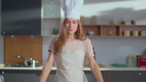 Улыбающийся шеф-повар стоит на кухне. Женщина в шляпе шеф-повара скрещивает руки на кухне — стоковое видео