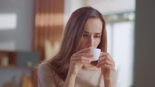 Удовлетворенная женщина пьет чай на кухне. Леди наслаждается чашкой кофе дома — стоковое видео