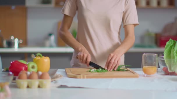 Γυναίκα κοπής κρεμμυδιών σε ξύλινη σανίδα στην κουζίνα. Νοικοκυρά ετοιμάζει σαλάτα — Αρχείο Βίντεο