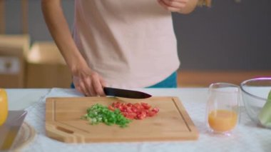 Ev hanımı mutfaktaki tahta tahtada sebze doğruyor. Domates yiyen kadın.