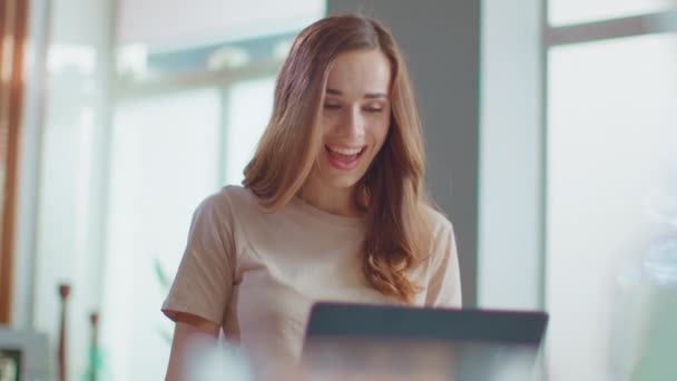 Zakenvrouw ontvangt goed nieuws op laptop. Dame eet cornflakes op keuken — Stockvideo