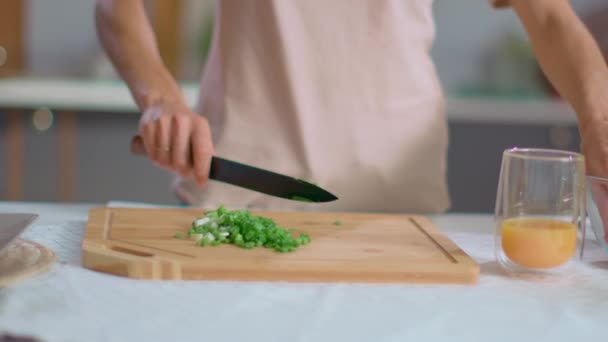 Жінка нарізає вишневі помідори на обробній дошці на кухні. Дівчина готує салат — стокове відео