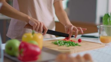 Tahta tahtada sebze doğrayan bir kadın. Gülümseyen kadın mutfakta salata pişiriyor.