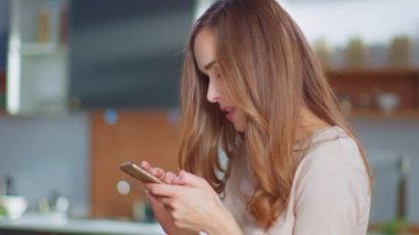Evde akıllı telefondan konuşan bir kadın. Mutfakta cep telefonu kullanan kız