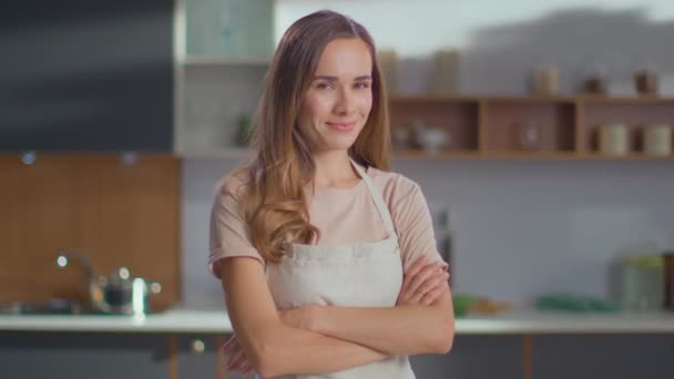 Wanita dengan tangan menyilangkan berdiri di dapur. Wanita memakai apron kompor di rumah — Stok Video