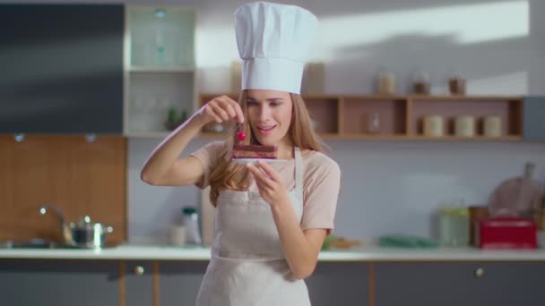 Bäcker dekorieren Kuchen mit Kirsche auf Küche. Köchin im Fertigdessert — Stockvideo