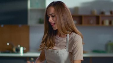 Attractive woman cooking on domestic kitchen. Woman using smartphone on kitchen