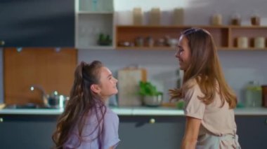 Woman and girl dancing on kitchen. Mother and daughter looking at each other