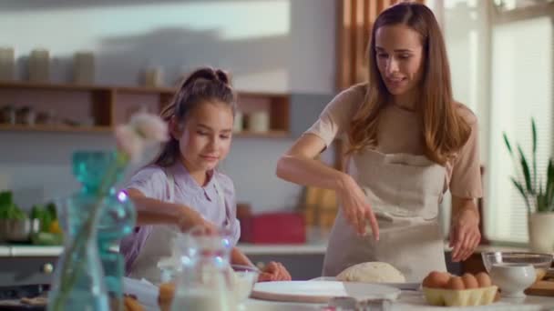 Niña y mujer rociando harina en la mesa en la cocina moderna — Vídeos de Stock