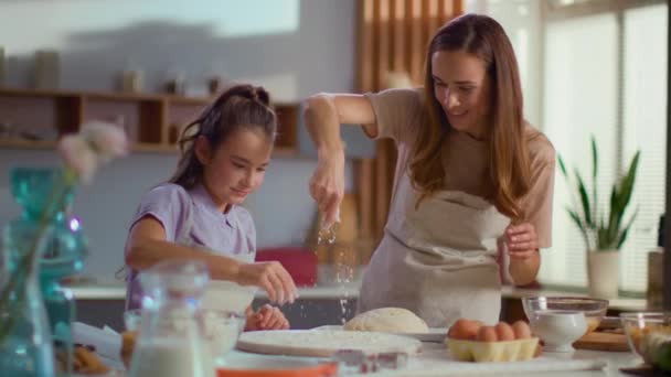 Madre e hija rociando harina en la mesa en la cocina de lujo — Vídeos de Stock