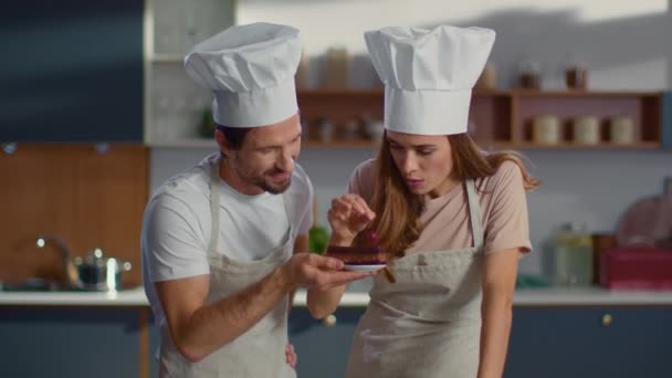 Baker y asistente poniendo cereza en la torta en la cocina. Un par de pasteleros. — Vídeos de Stock