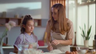 Mother smearing daughter nose in flour on kitchen in slow motion