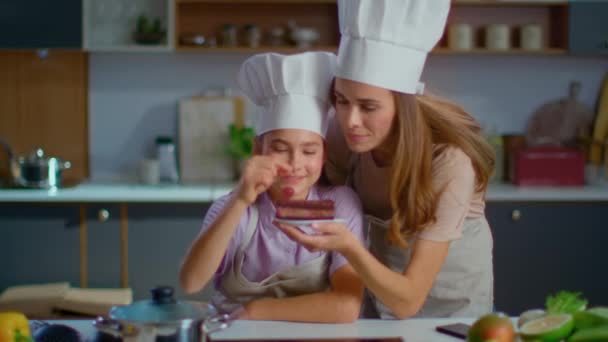 Pastelera y madre poniendo cereza en la torta en la cocina en cámara lenta — Vídeos de Stock