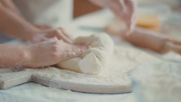 Mother hands helping daughter to knead dough on table at home — 비디오