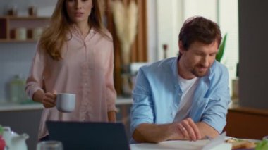 Businessman and woman using laptop at home. Man and woman talking on kitchen