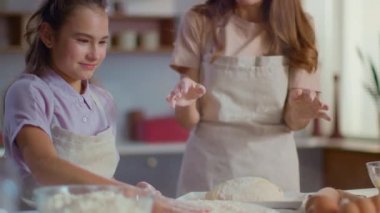 Woman and girl clapping hand on flour at modern kitchen in slow motion