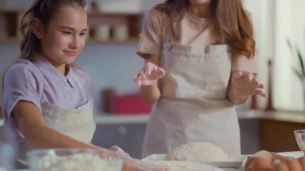 Женщина и девушка хлопают в ладоши о муку на современной кухне в замедленной съемке — стоковое видео