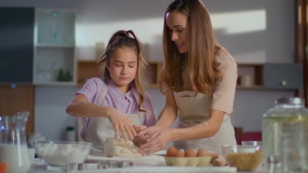 Madre enseñando a su hija a amasar masa para galletas en la cocina en cámara lenta — Vídeo de stock