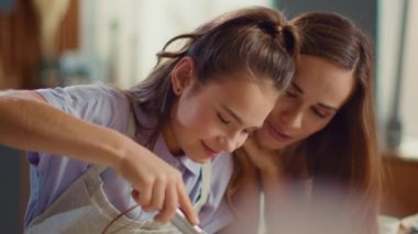 Kadın ve kız mutfakta yumurta çırpıyor. Kız ve anne birlikte yemek pişiriyorlar.