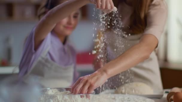 Mujer y niña rociando harina en la mesa en la cocina en cámara lenta — Vídeos de Stock