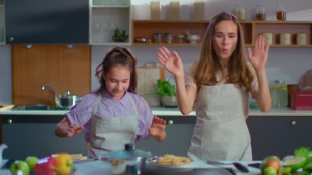 Радісна дівчина і жінка танцюють як роботи на кухні в повільному русі — стокове відео