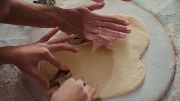 Closeup woman and girl cutting dough with cookie cutters on kitchen table — Stock videók