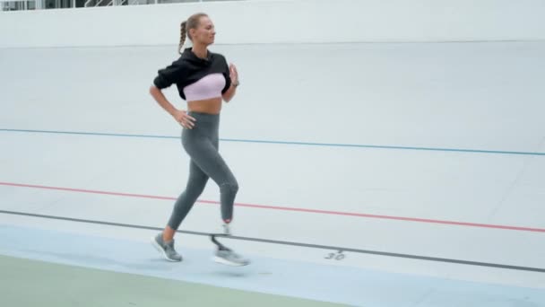 Funktionshindrade idrottskvinna som springer på sportbanan. Sportkvinna joggar på kapplöpningsbanan — Stockvideo