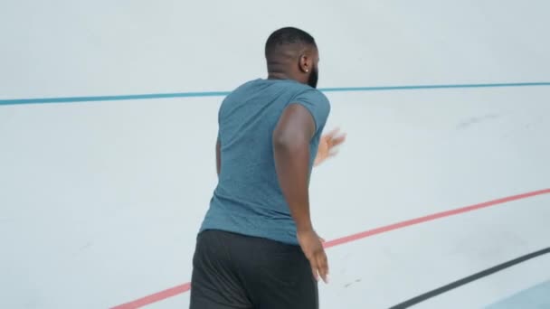 Afro man loopt op de rails. Mannelijke loper joggen op atletiek track — Stockvideo