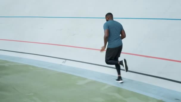 Afro löpare utbildning på sportbanan. Sportig man som springer på friidrott spår — Stockvideo